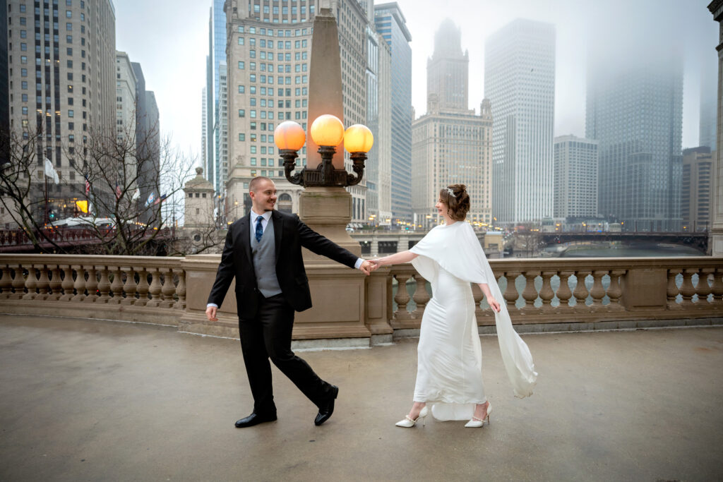 Bride and groom holding hands on a foggy downtown Chicago bridge during an intimate winter elopement.