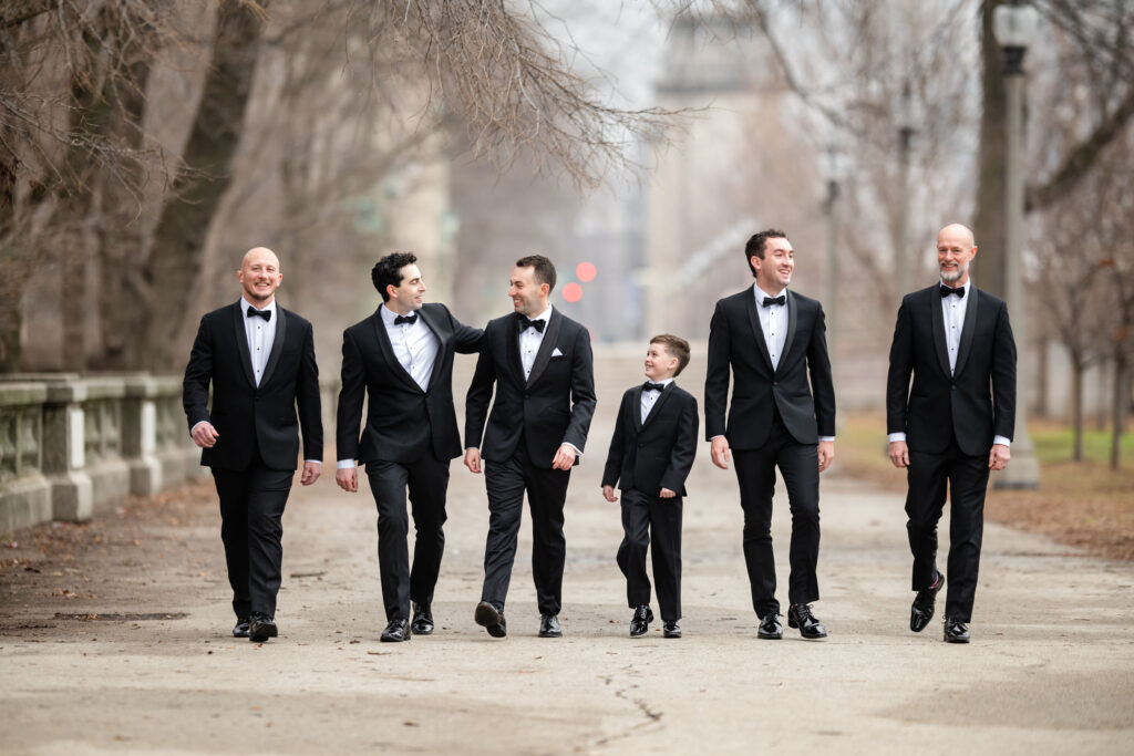 Groom and groomsmen walking together in black tuxedos during winter wedding portraits in Chicago before the ceremony