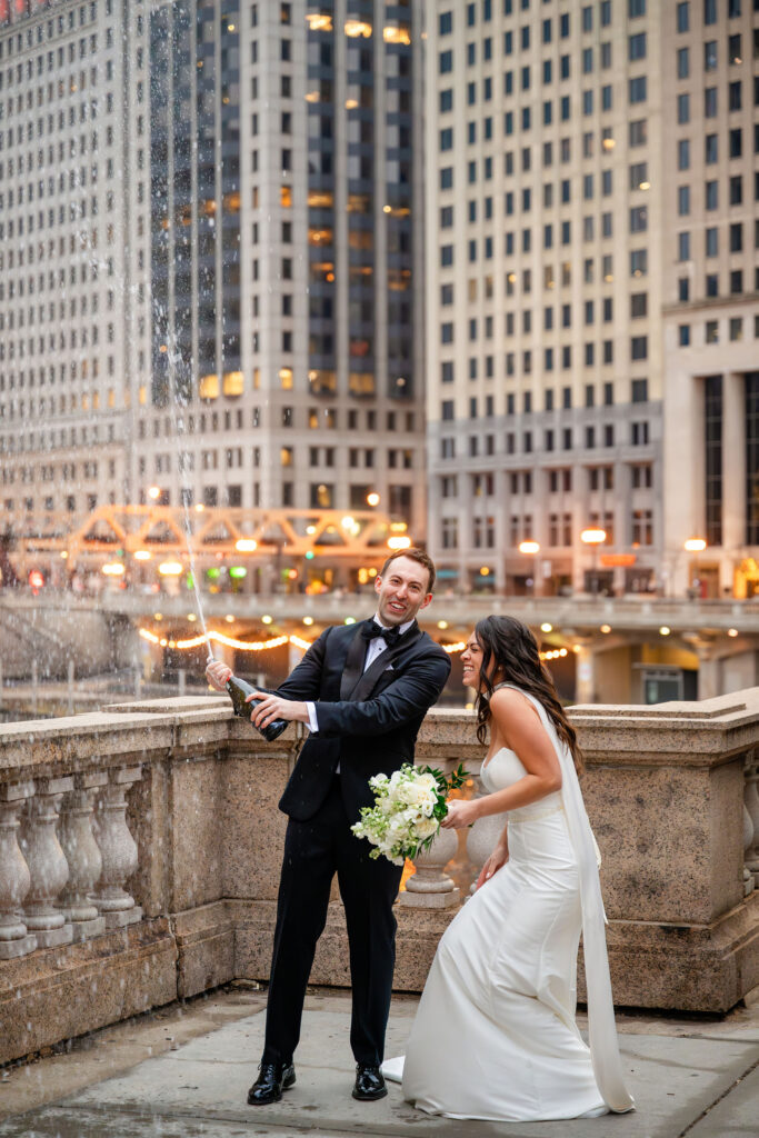 Bride and groom celebrating with a champagne pop along the Chicago River after a winter wedding