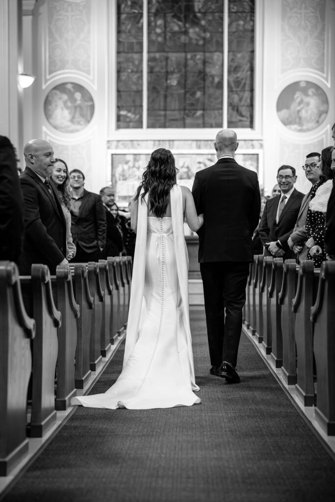 Bride and dad walking down the aisle during a Catholic wedding ceremony in Chicago