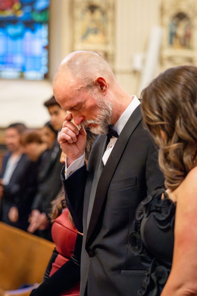 Father of the bride wiping away tears during the wedding ceremony at Assumption Catholic Church in Chicago