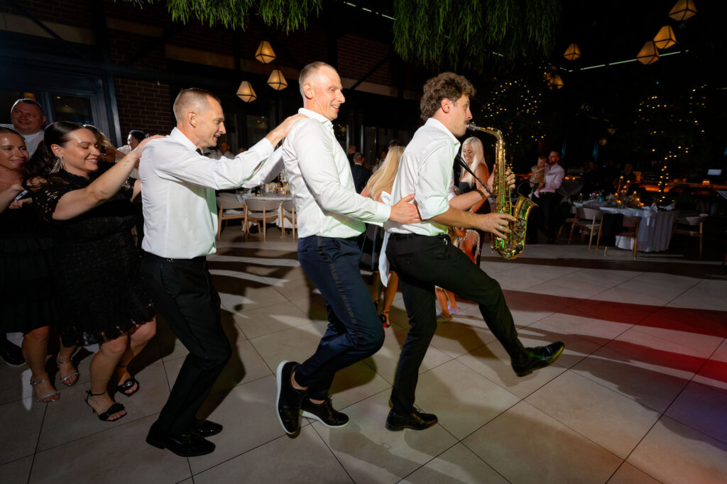 Wedding guests dancing with a live saxophonist on the dance floor during a high-energy reception at Pella Signature.